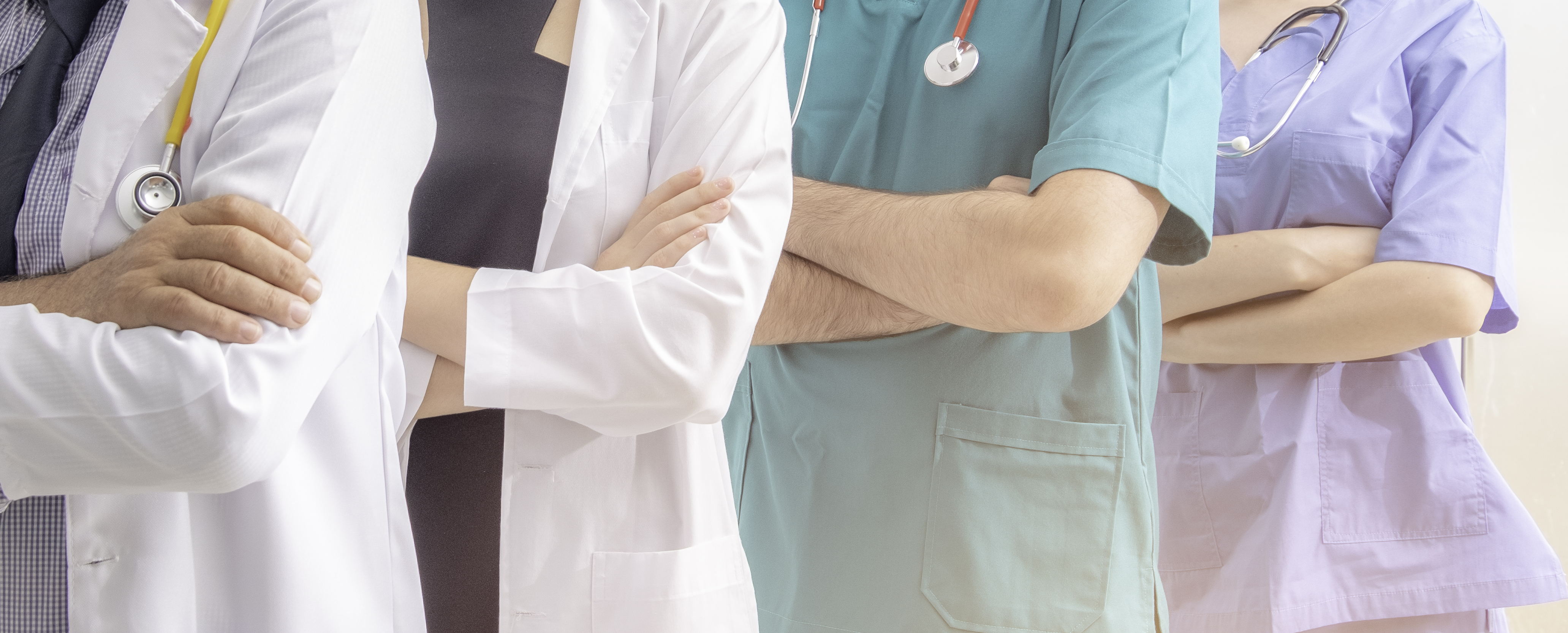 person-wearing-white-lab-coat-next-to-person-with-crossed-arms-wearing-blue-green-scrubs-and-stethoscope